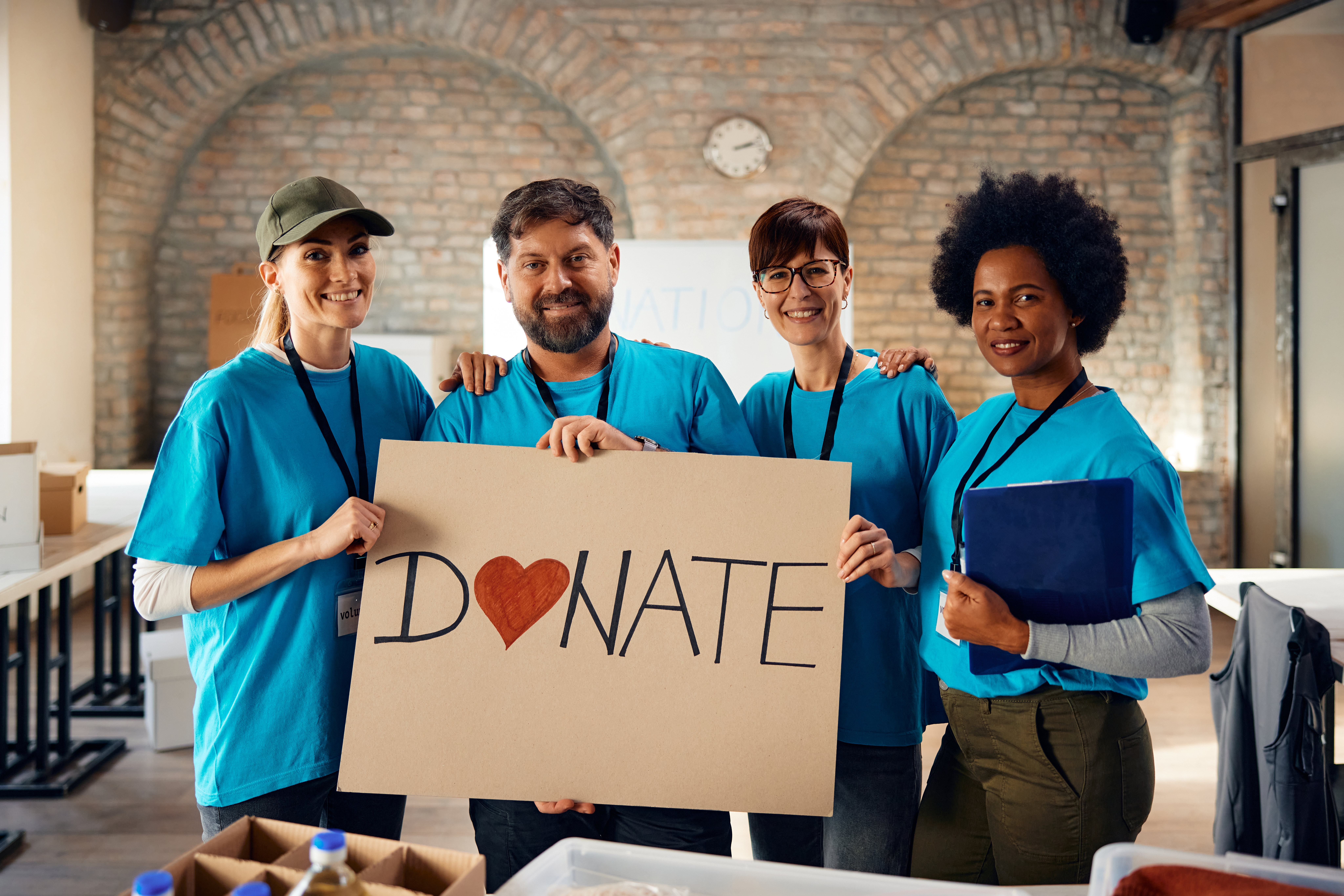 Diverse volunteers inviting people to donate to charity and looking at camera.